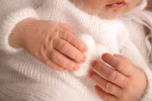 Newborn’s hands on soft blanket symbolize hope after egg freezing in Greece, a gentle outcome of modern fertility science.