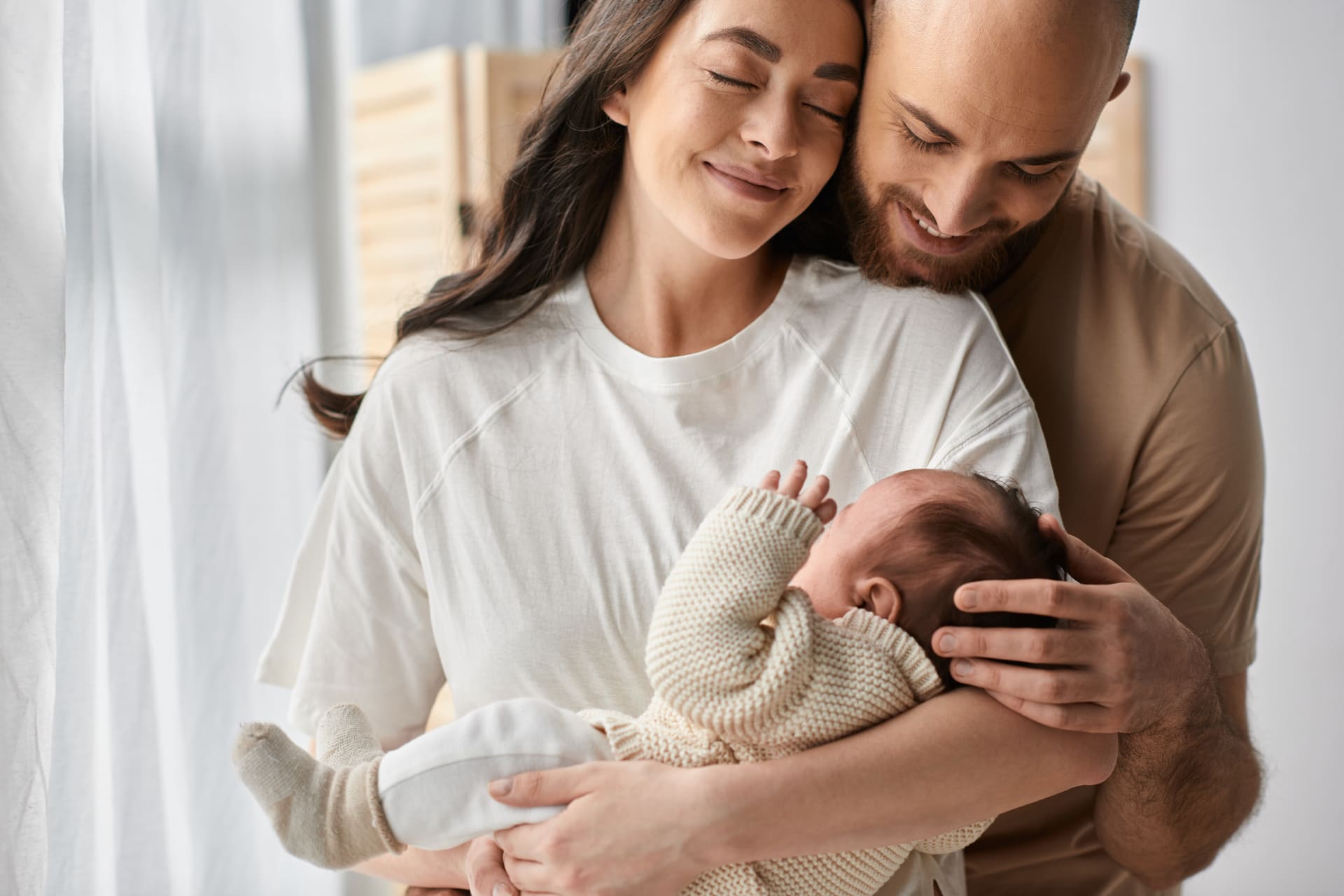 New parents gently hold their newborn, celebrating the joy of successful IVF after overcoming hydrosalpinx fertility challenges together.