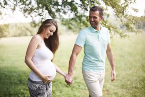 Pregnant woman and partner stroll outdoors, symbolizing IVF triumph and renewed hope after hydrosalpinx treatment and care.