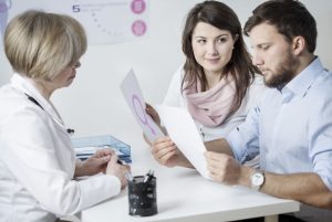 Eine Fruchtbarkeitsspezialistin berät ein Paar mit weiblichem Symbol, das die icsi-ivf-Planung und Patientenbildung verdeutlicht.