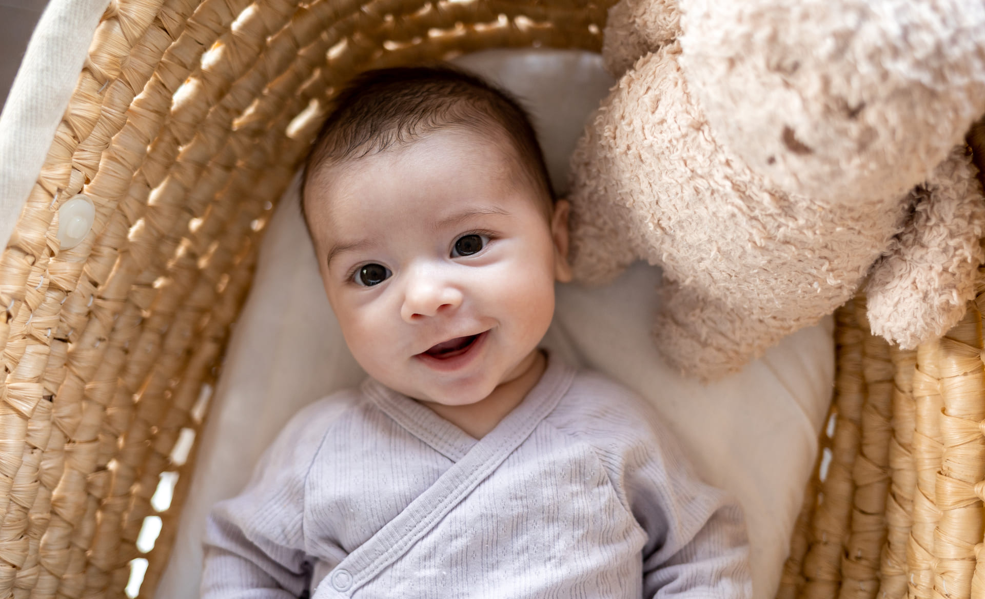 Newborn baby smiles happily in woven basket, symbolizing comfort and joy after IVF.