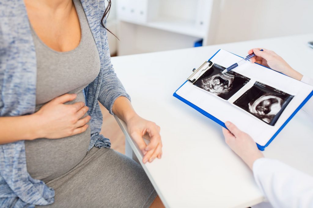 IVF-Schwangerschafts-Ultraschall-Bewertung mit Patientin und Facharzt, bespricht fetale Entwicklung und bestätigt gesunden Schwangerschaftsverlauf.
